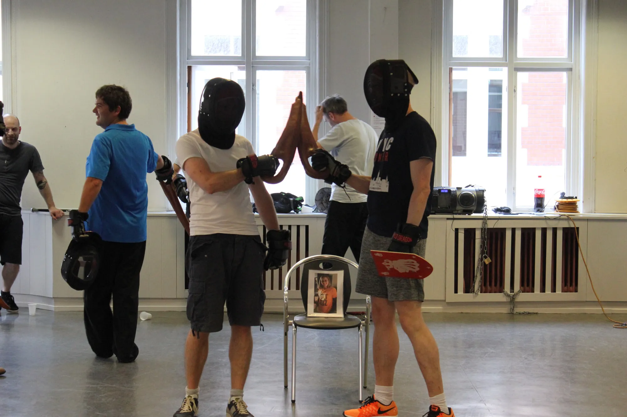 Two participants at a stag party fencing each other in masks and gloves.