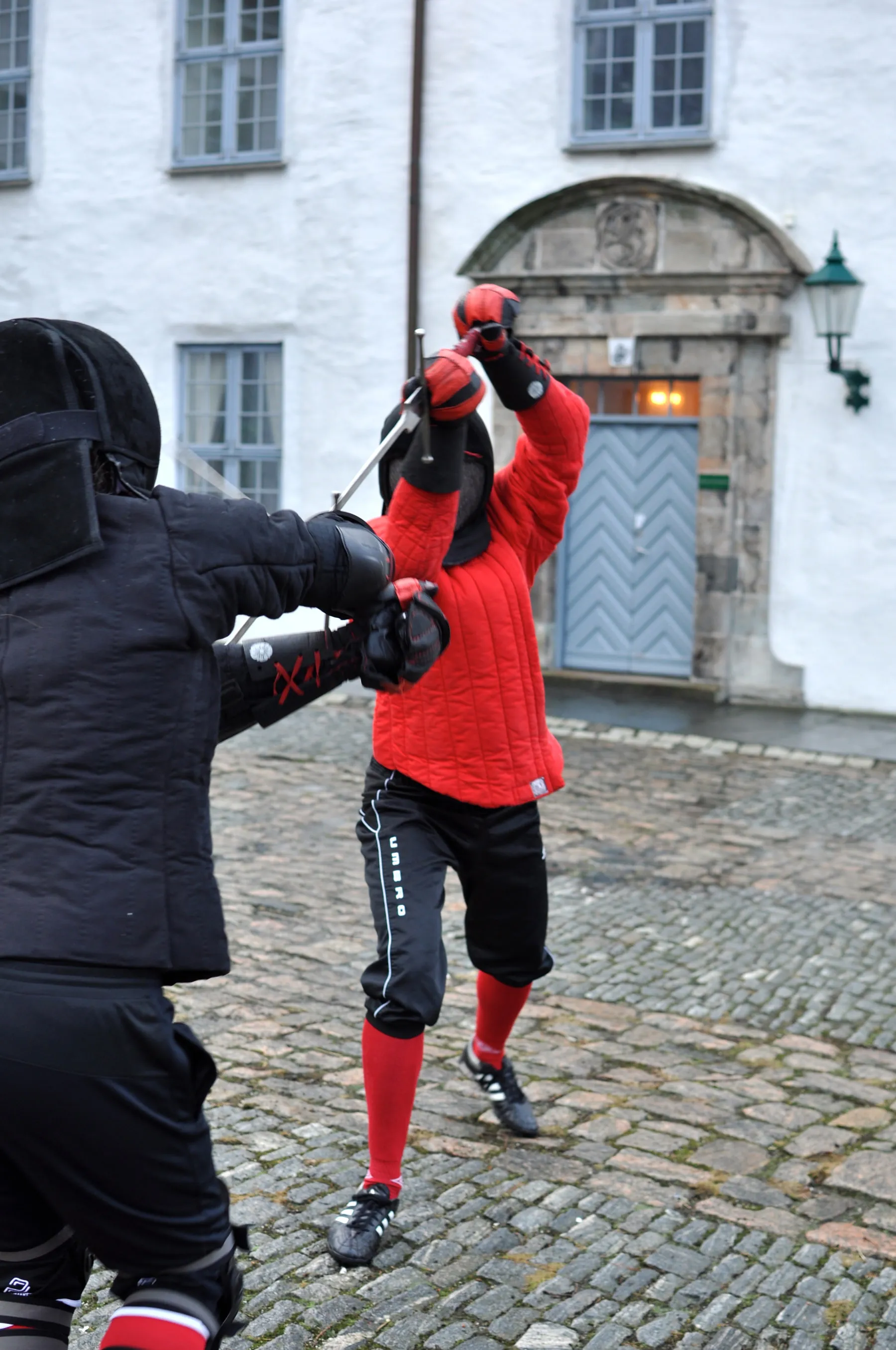 Two fencers in a bind with their swords raised overhead.